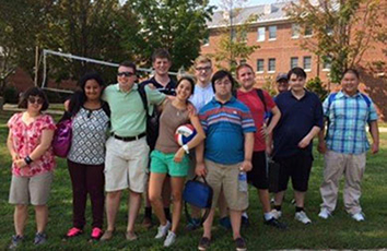 Eleven students pose in front of a volleyball net outside on the Middlesex campus