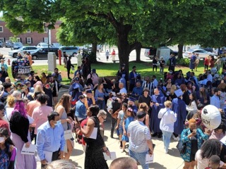 Gathering after college graduation ceremony on a sunny spring afternoon.